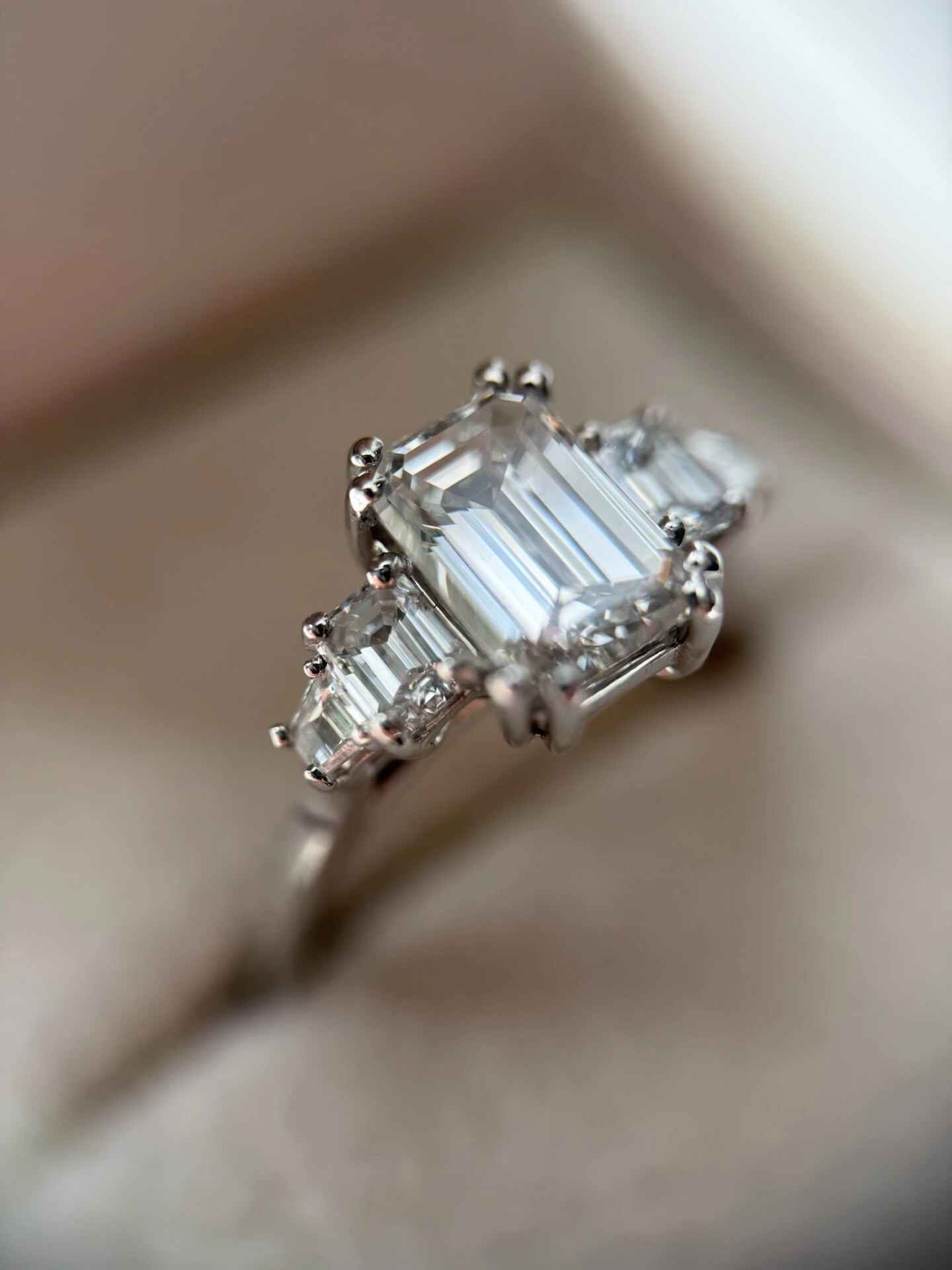 Solitairering med emerald cut diamant og baguettester i hvidguld