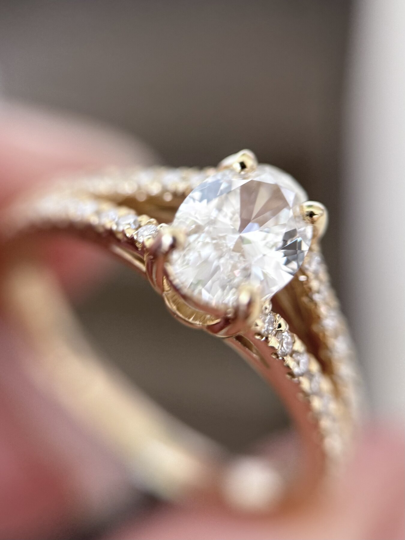 Ring med oval diamant og pavéfattede sidesten i gulguld